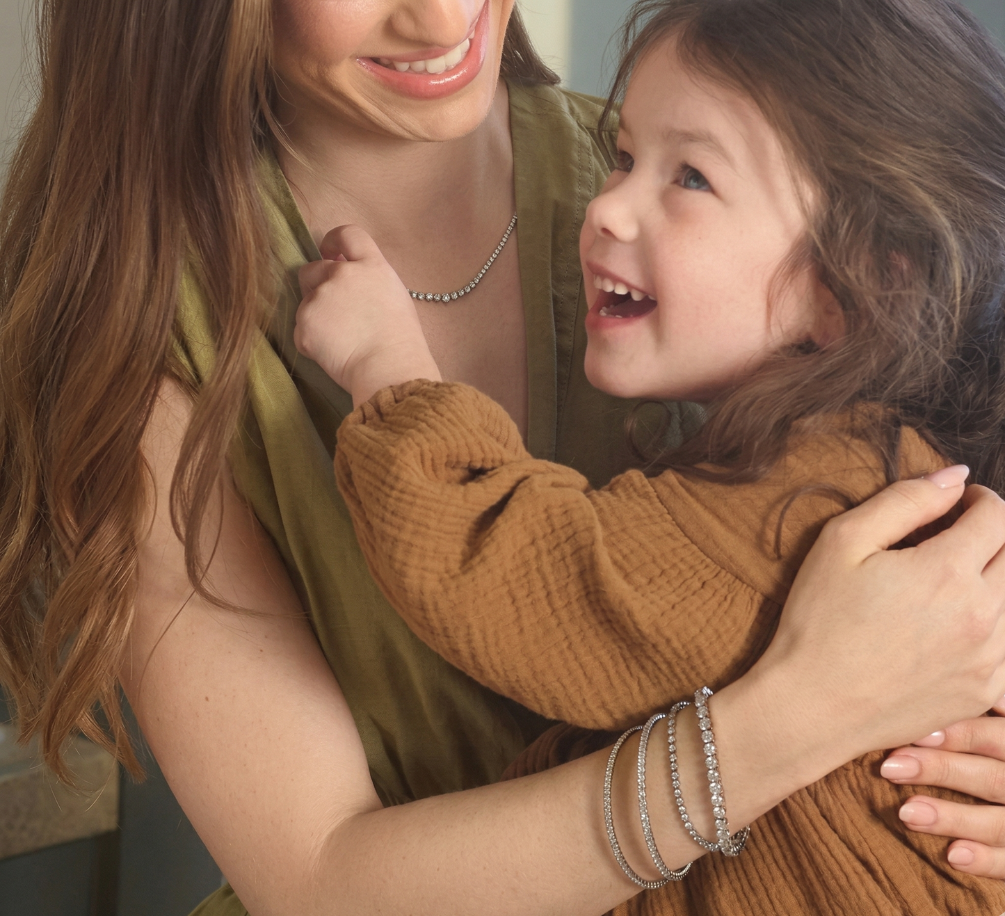 Model wearing 14K yellow gold 3 CTW lab-grown diamond flexible bangle bracelet while hugging a child