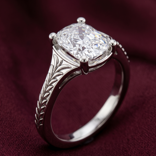 Front view of cushion cut solitaire engagement ring in 14K white gold featuring a large sparkling cushion cut diamond and detailed leaf engraving on the band