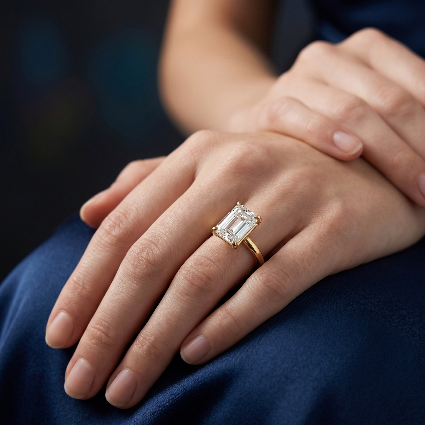 Emerald cut solitaire engagement ring with 2.50 CT lab-grown diamond worn on a woman’s hand in a soft lifestyle setting