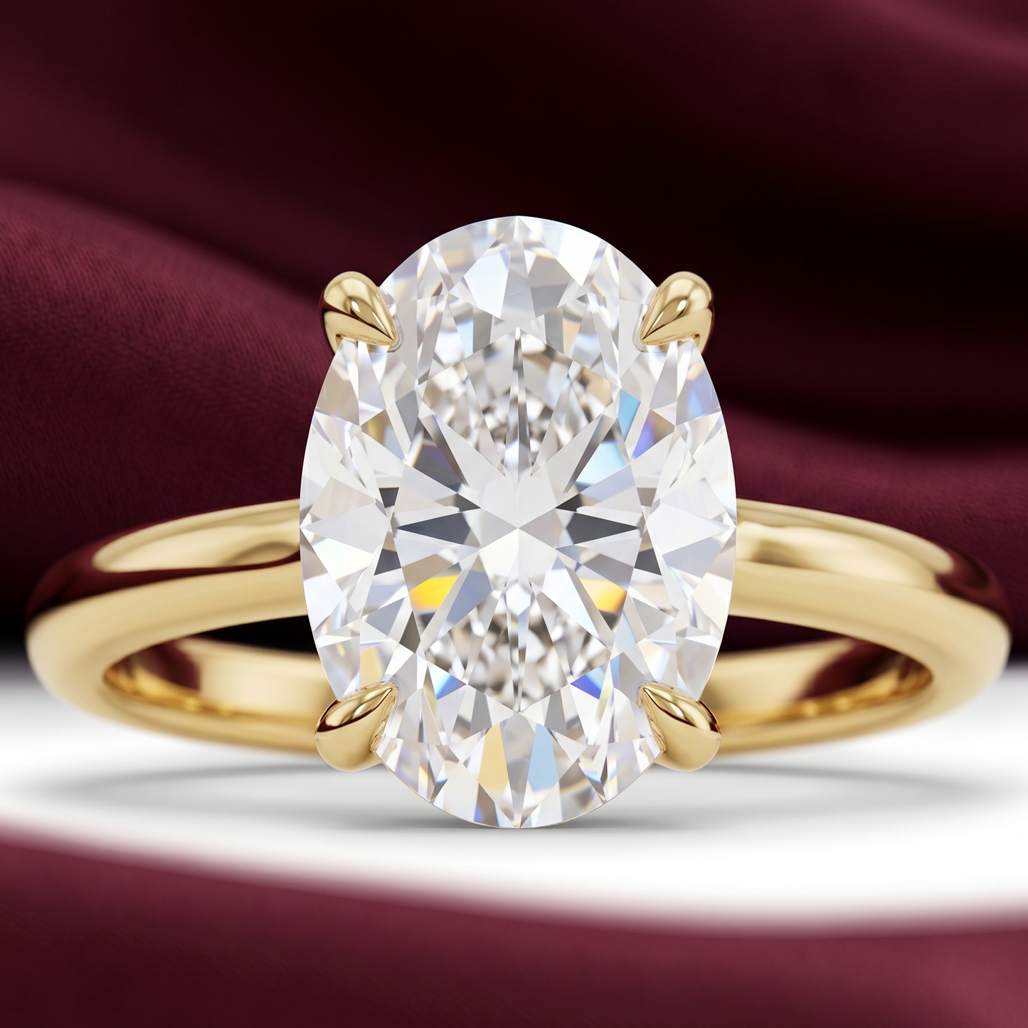 Close-up of oval solitaire engagement ring in yellow gold with 2.70 CT oval diamond on a burgundy fabric background