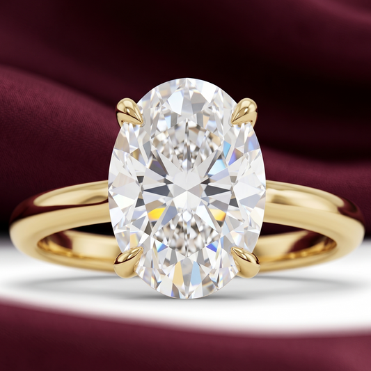 Close-up of oval solitaire engagement ring in yellow gold with 2.70 CT oval diamond on a burgundy fabric background